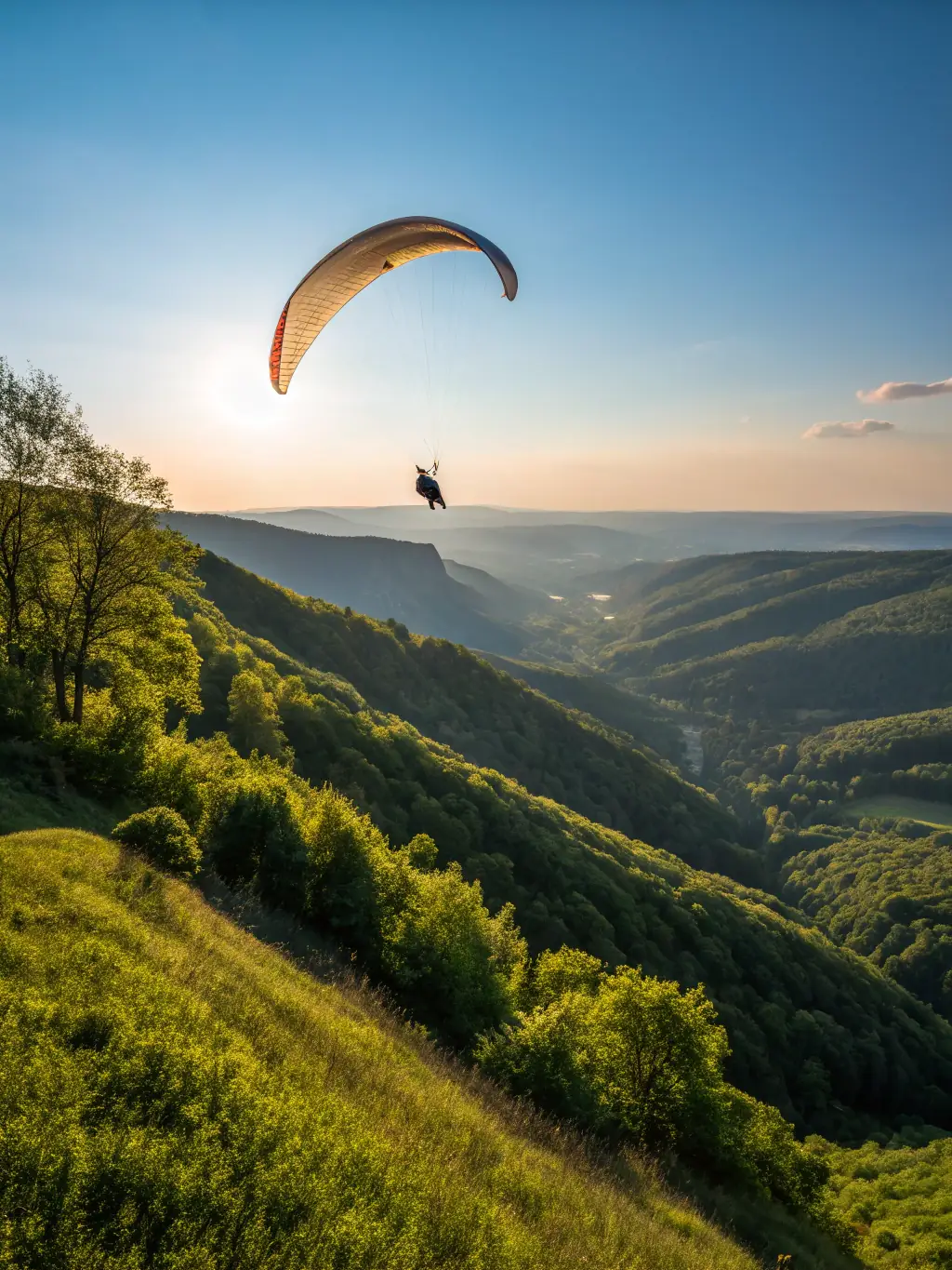 A pilot using a variometer during a paragliding flight, with the landscape visible in the background.